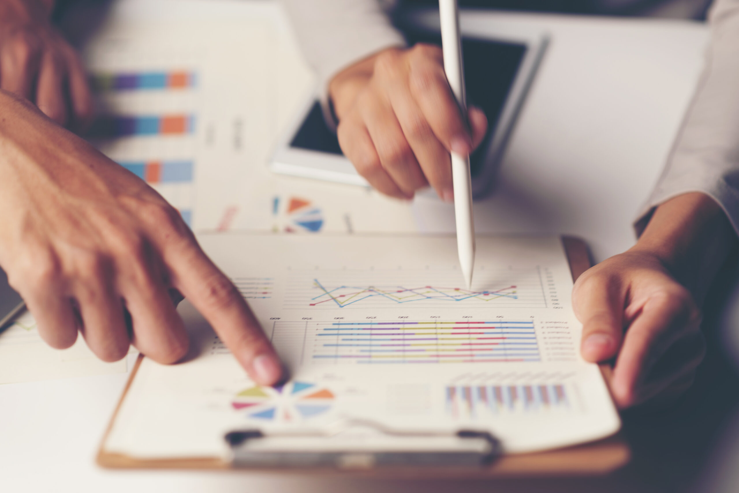 Two hands analyze colorful graphs and charts on a clipboard | Jacko Law Group, PC