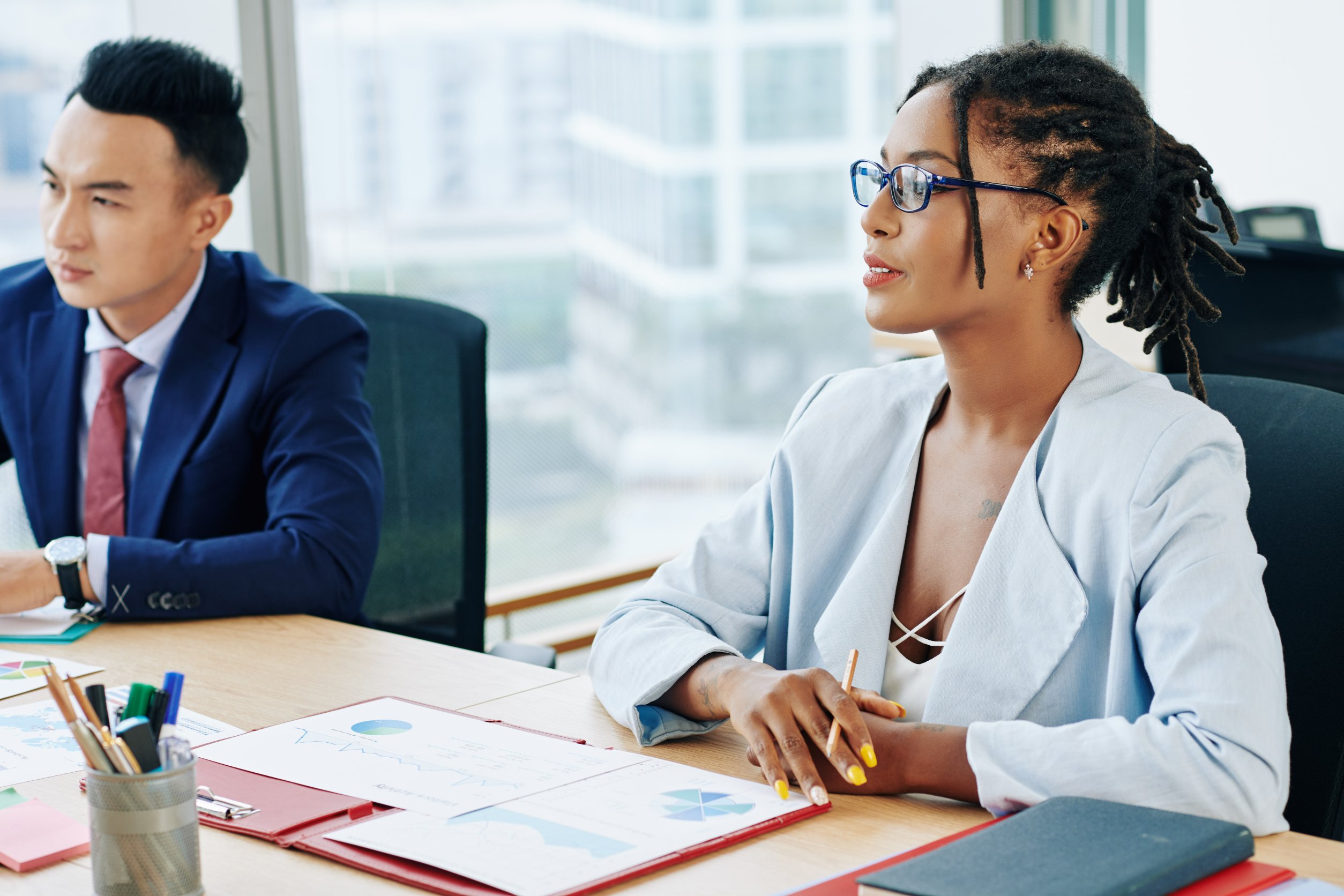 A woman and a man in a navy suit sit at a conference table | Jacko Law Group, PC