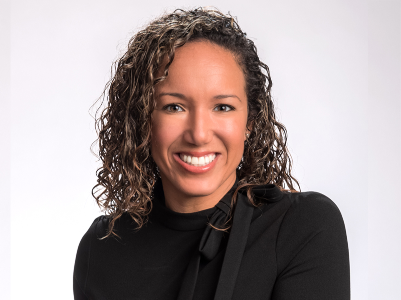 A woman with curly hair dressed in a black shirt | Jacko Law Group, PC