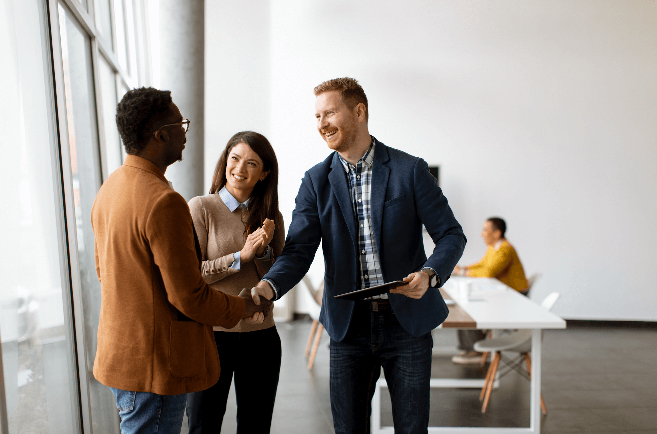 Three professionals engage in a handshake in a office | Jacko Law Group, PC