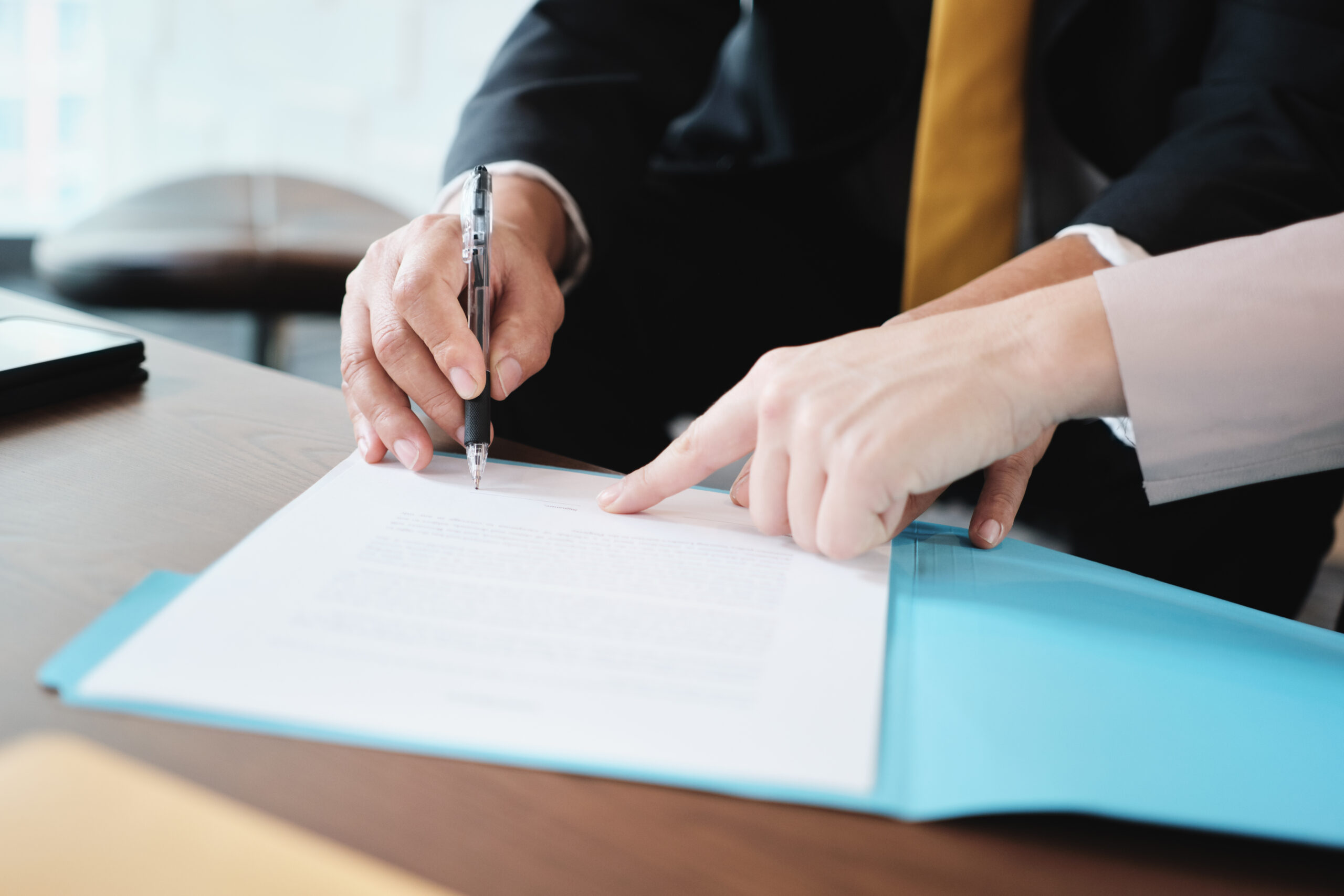 Two professionals signing a document at a desk | Jacko Law Group, PC