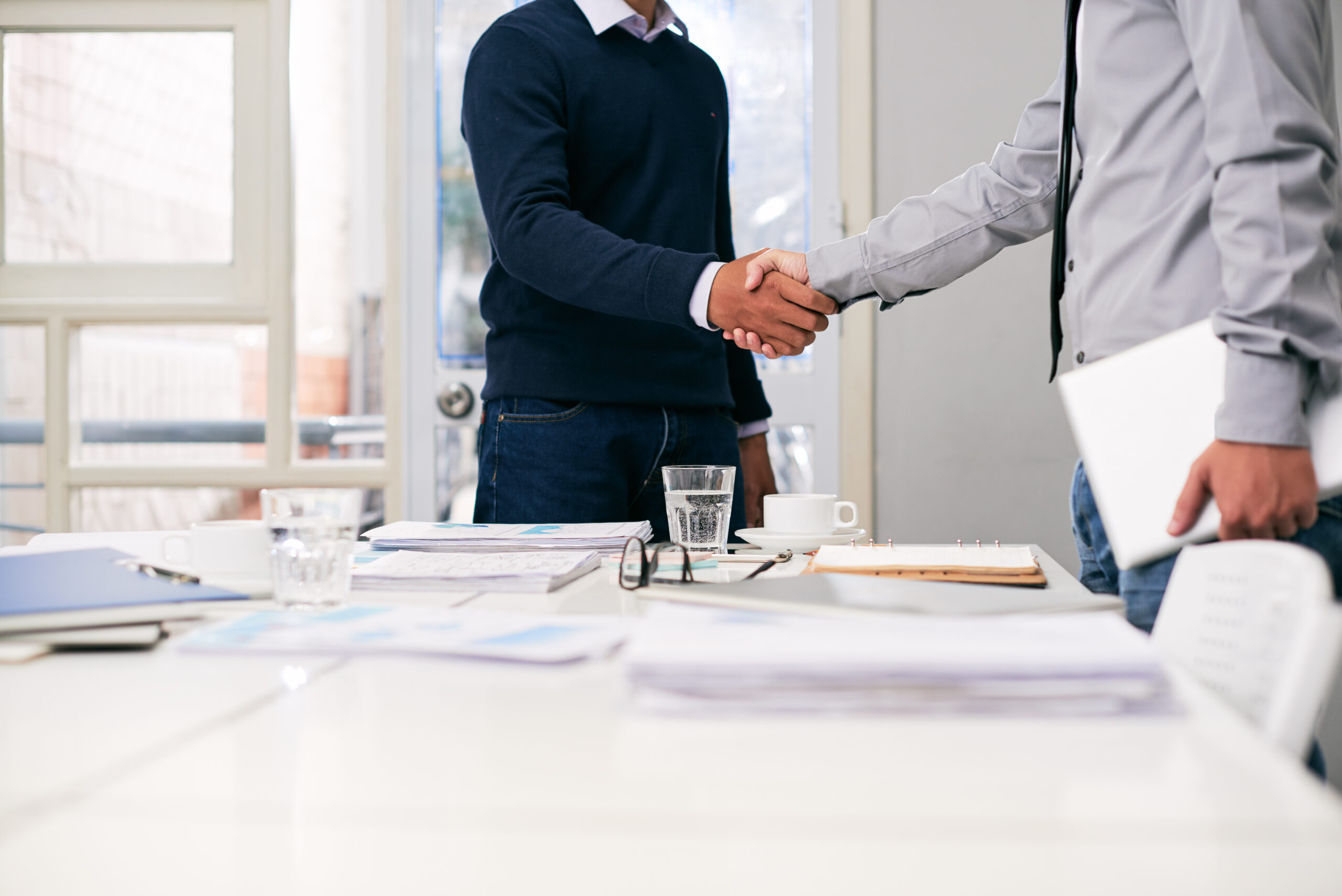 Two business professionals shake hands across a table | Jacko Law Group, PC