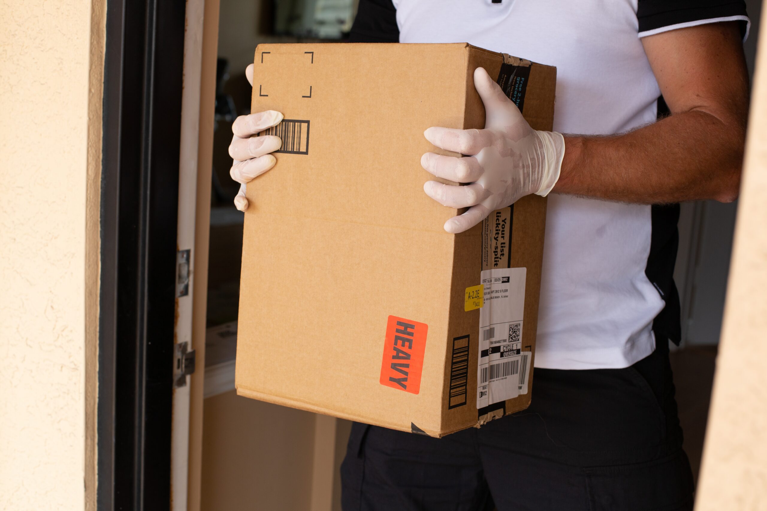 A person wearing white gloves holds a heavy box package | Jacko Law Group, PC