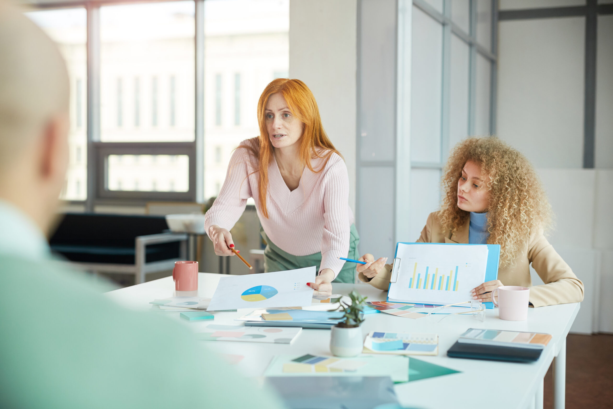 A woman stands at a conference table, gesturing toward charts and graphs | Jacko Law Group, PC
