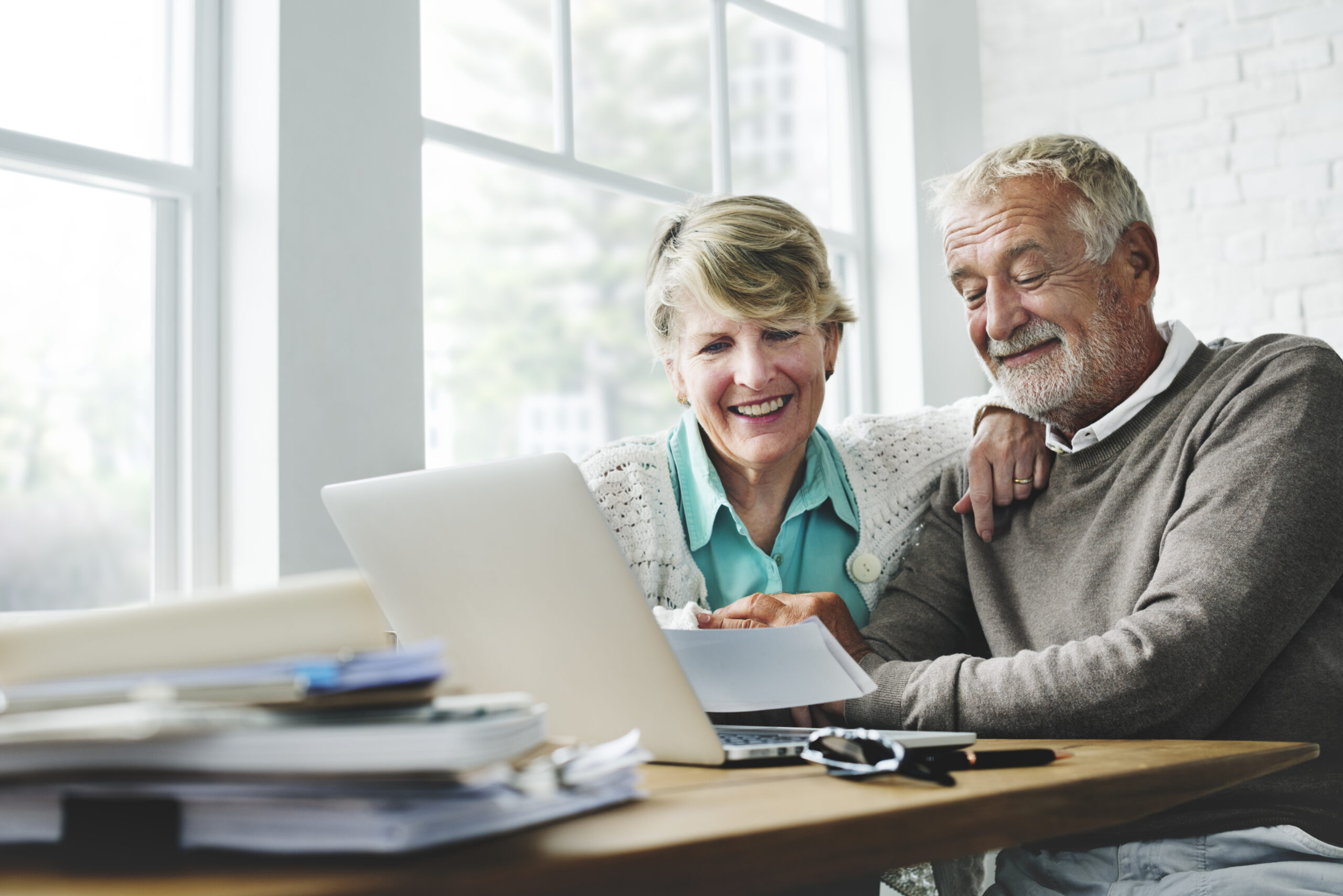 An older couple smiles together while viewing a laptop | Jacko Law Group, PC